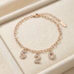 Brățară placată cu aur roz, reglabilă 17+3 cm, cu pandantive cifre 520 și cristale, Noem®