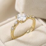 Inel placat cu aur 14K, model fin cu piatră centrală rotundă și cristale laterale, mărimea 6, Noem®