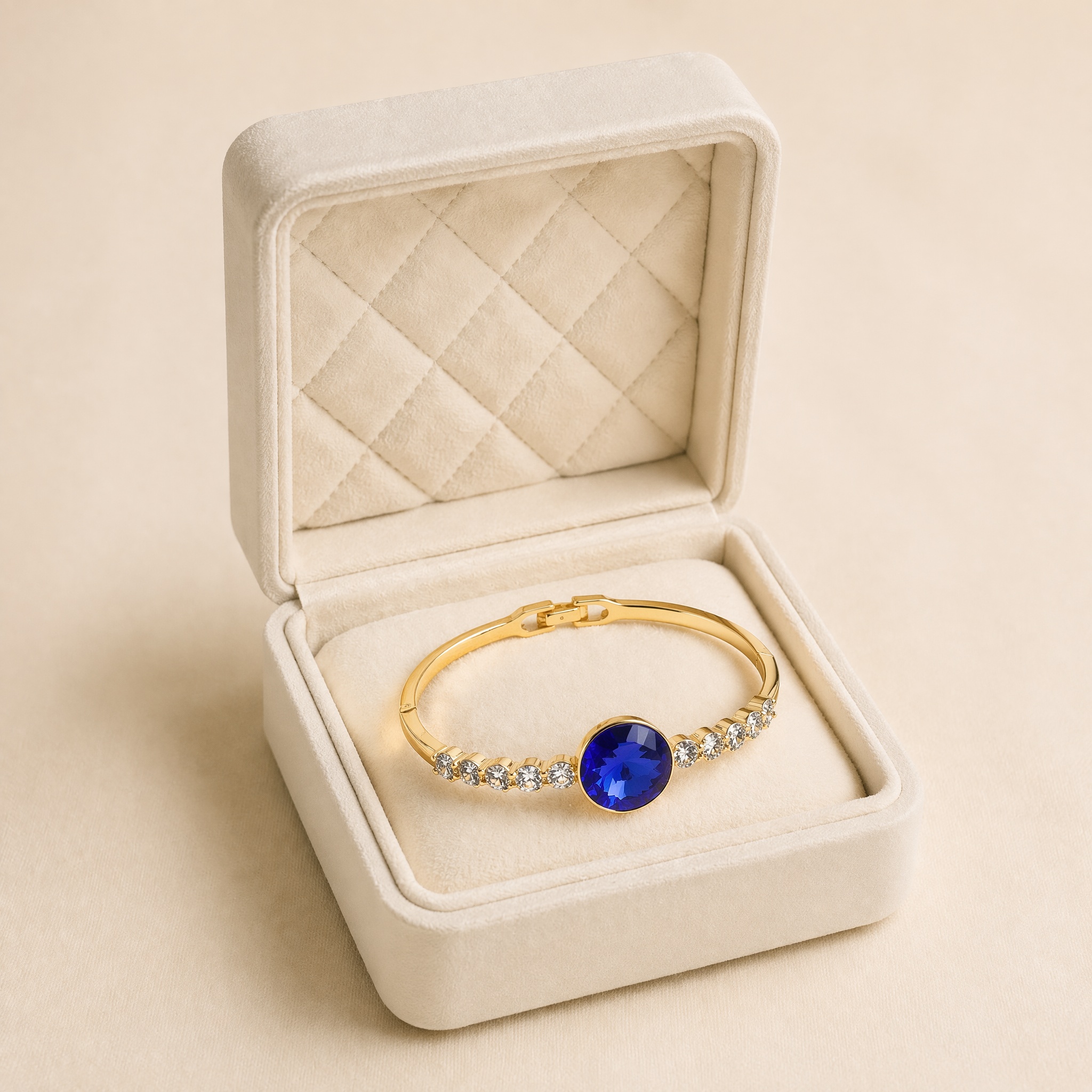 bratara_5_oval_albastru_cutie_2 Brățară fixă placată cu aur de 14K, model elegant cu un cristal central rotund de un albastru-safir intens încadrat de linii din pietre mici strălucitoare, 59/11 mm, Noem® - imagine 1