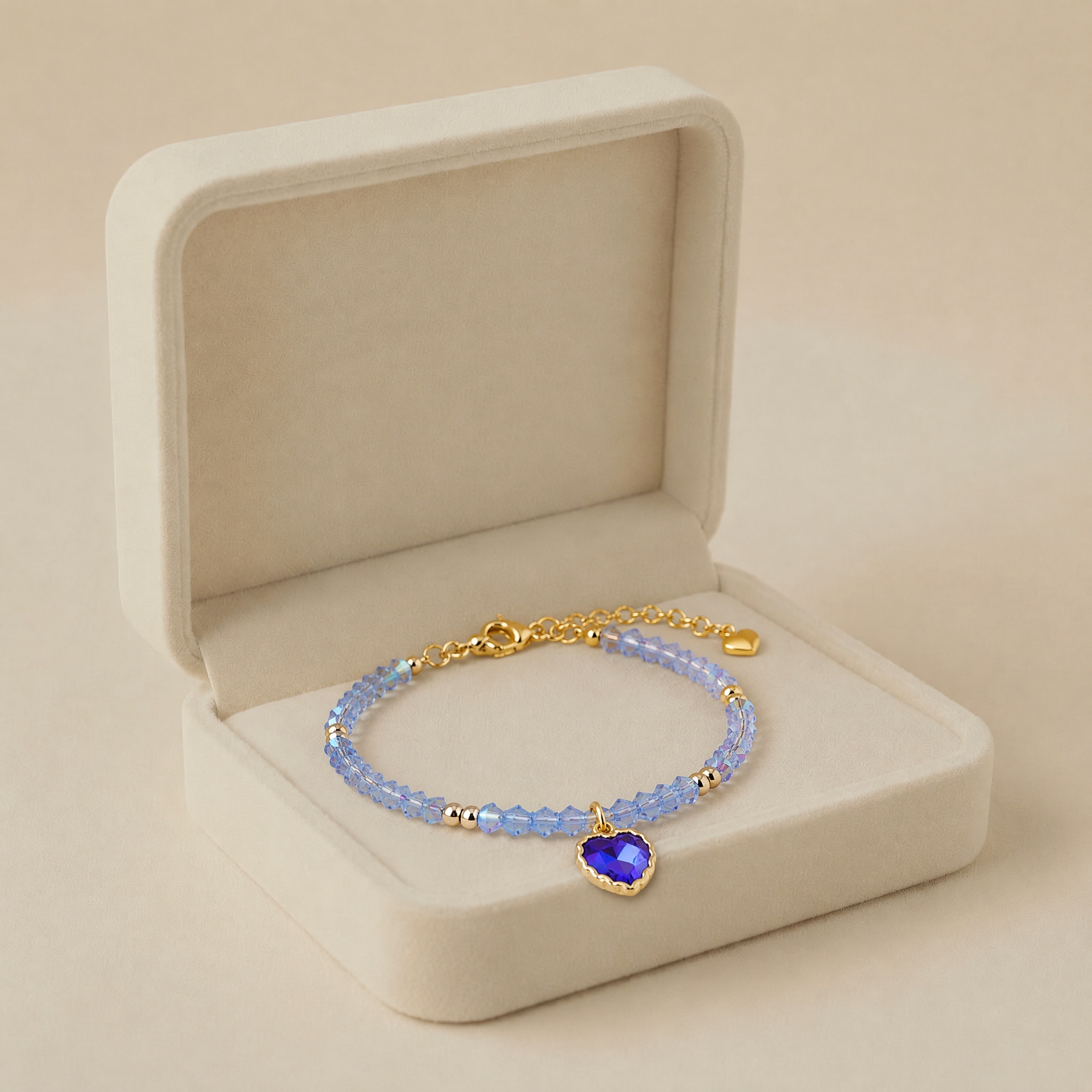 bratara_albastra_in_cutie_noem_2 Brățară romantică din mărgele sferice albastru-pastel cu tăietură fațetată, accesorizată cu pandantiv inimă din cristal de safir în ramă din oțel inoxidabil placat cu aur de 14K, Noem® - imagine 1